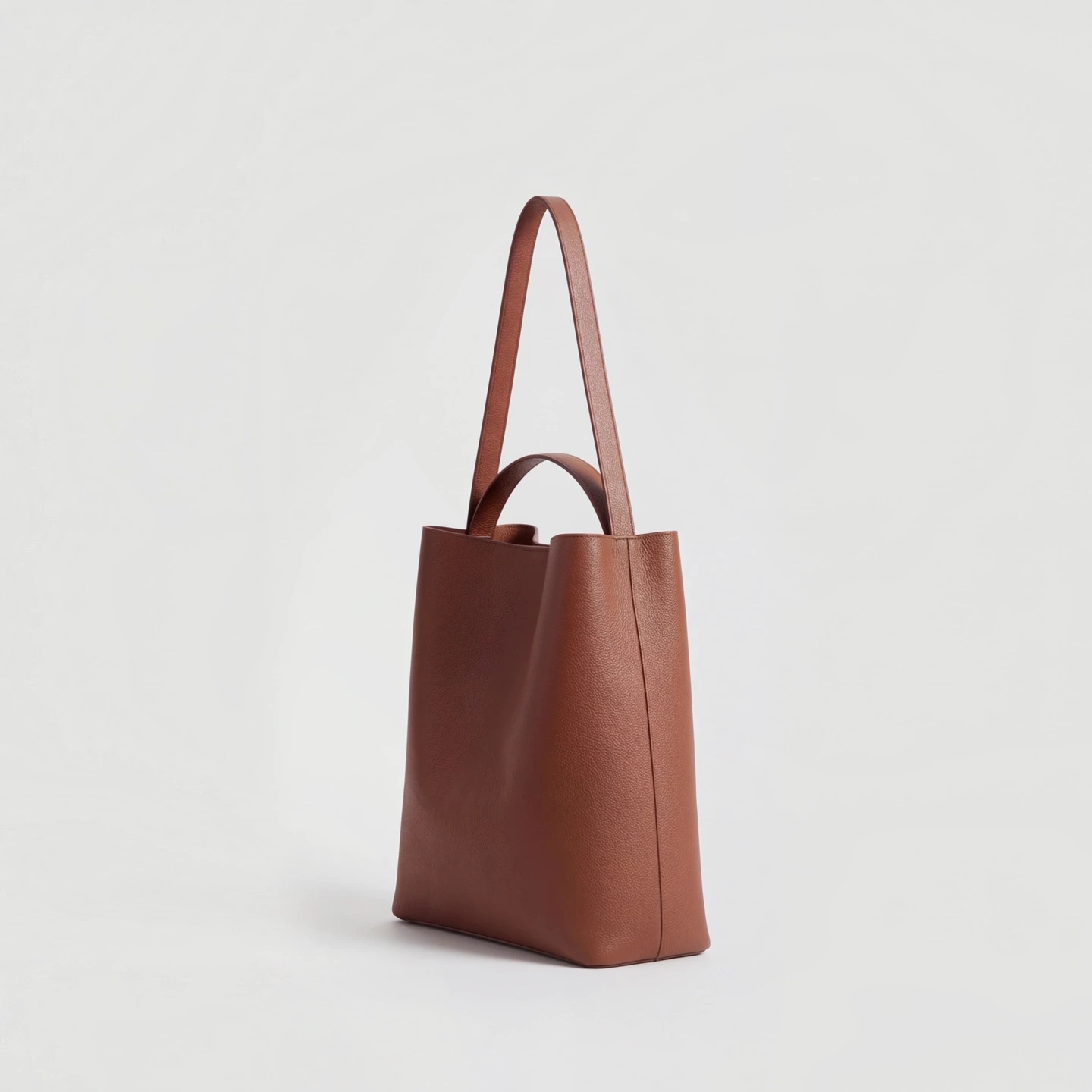 A brown leather tote, turned three-quarter.